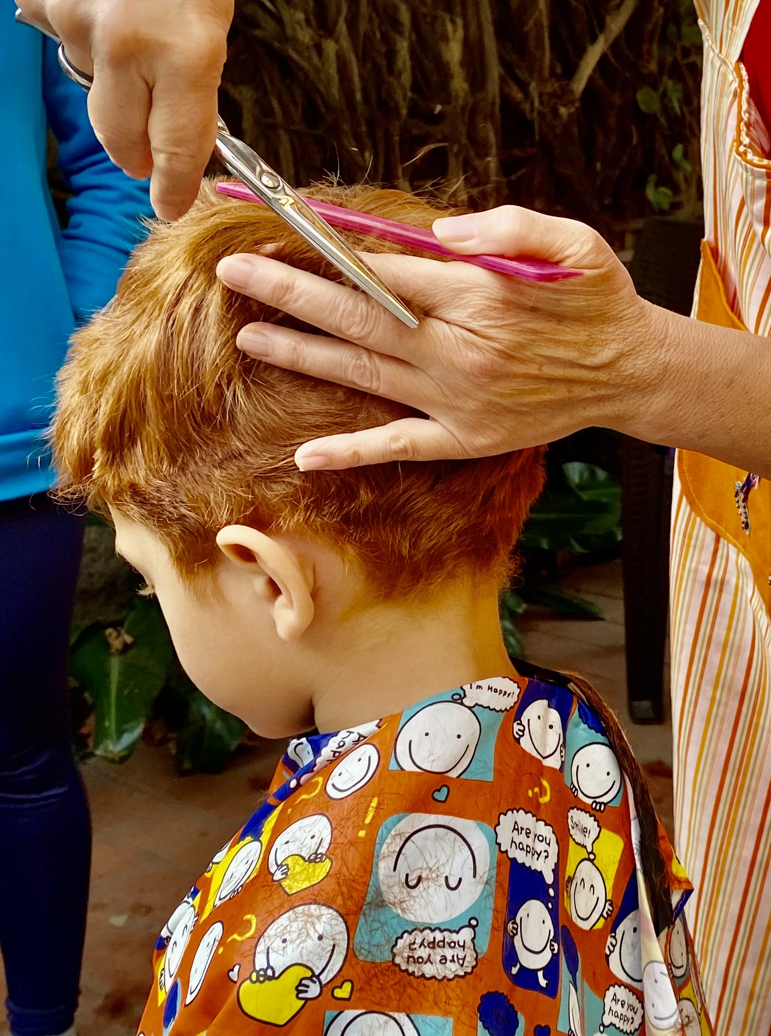Peluquera recorta el cabello de un niño con tijeras.